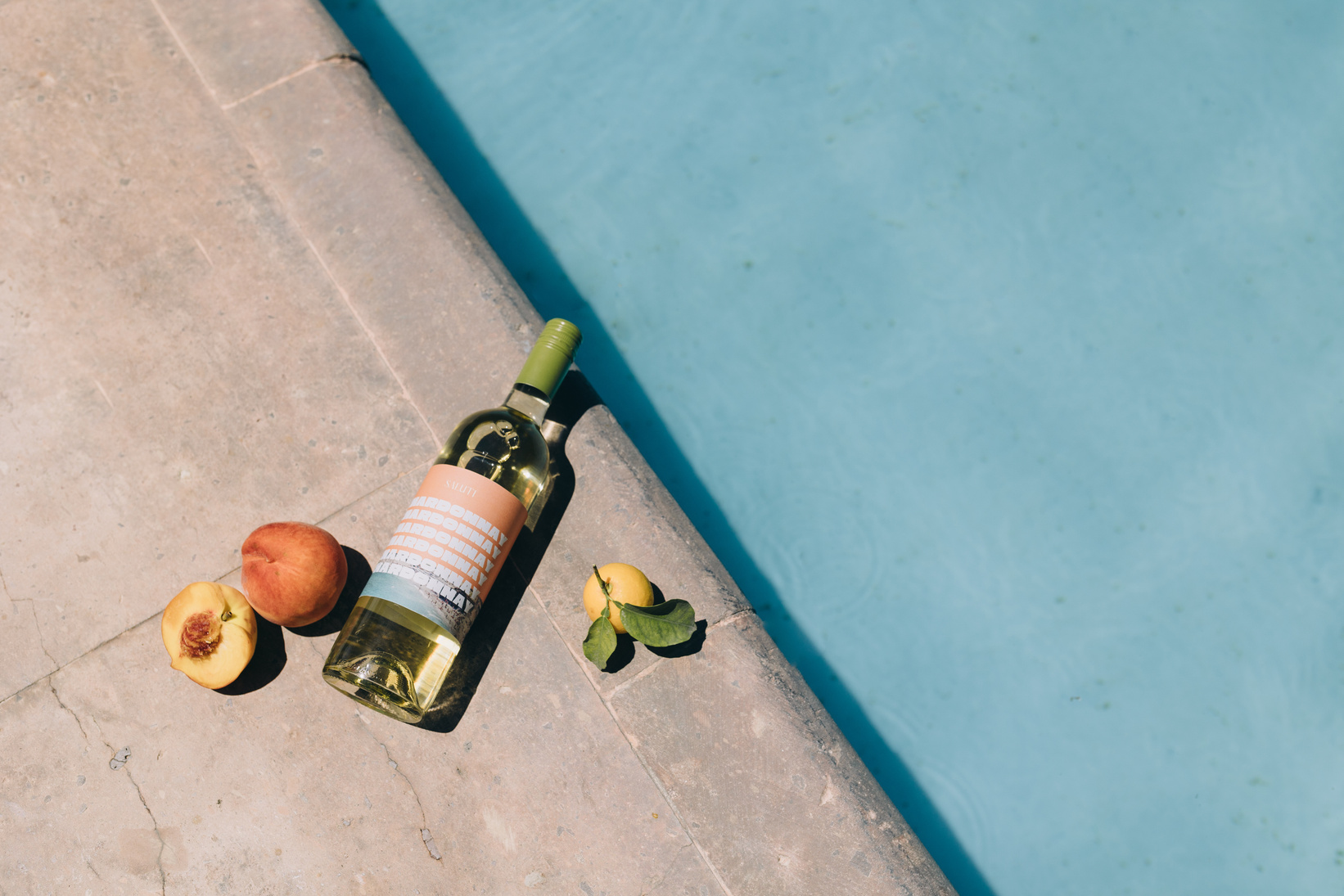 Top View of Wine Bottle and Fruit by the Pool
